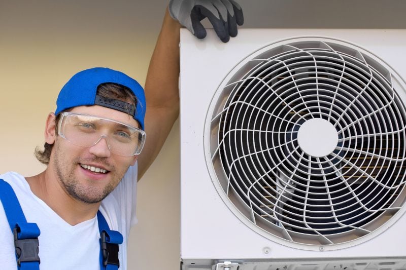 Fall HVAC Maintenance - Maintenance Man Standing by HVAC Unit.